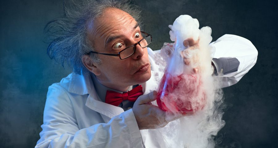 Scientist with wild white hair wearing a lab coat and holding a flash with steaming liquid.