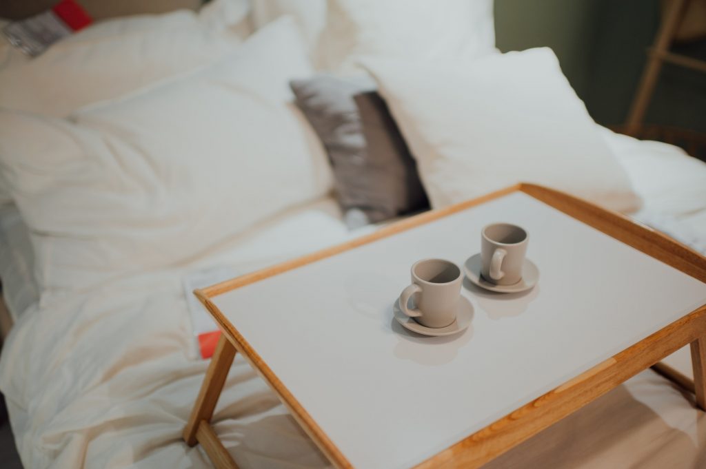 Two cups of coffee on a potable table placed on a bed