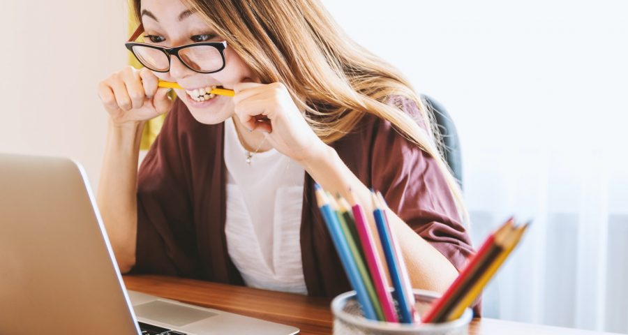 Photo of Asian female studying and biting pencil in frustration.