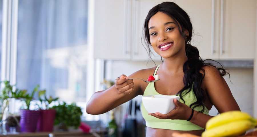 Image of young Black woman eating fruit salad.